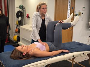 Veronika Cmolikova assessing an attendee's hip in supine on a treatment table during DNS Exercise Part I