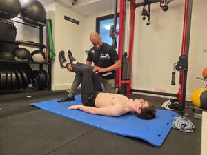 Attendees practising a supine leg-raise assessment in pairs during DNS Exercise Part I