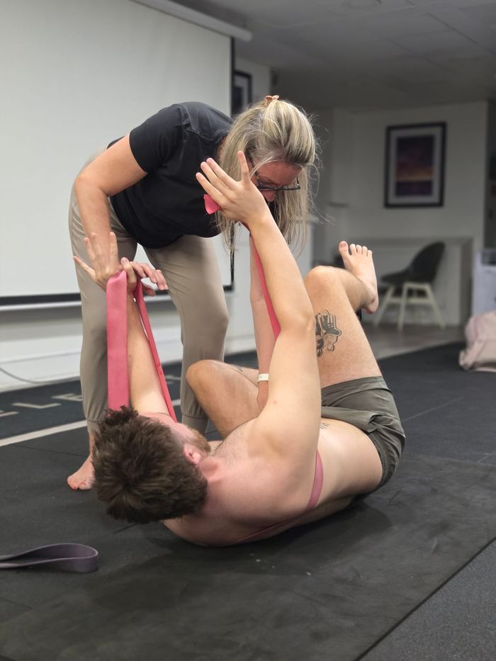 Instructor Zuzana Suzan guiding a resistance-band shoulder assessment during DNS Exercise Part III