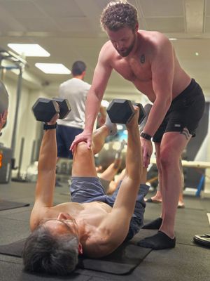 Attendee performing a dumbbell floor press with coaching during DNS Exercise Part III at Elevate LDN